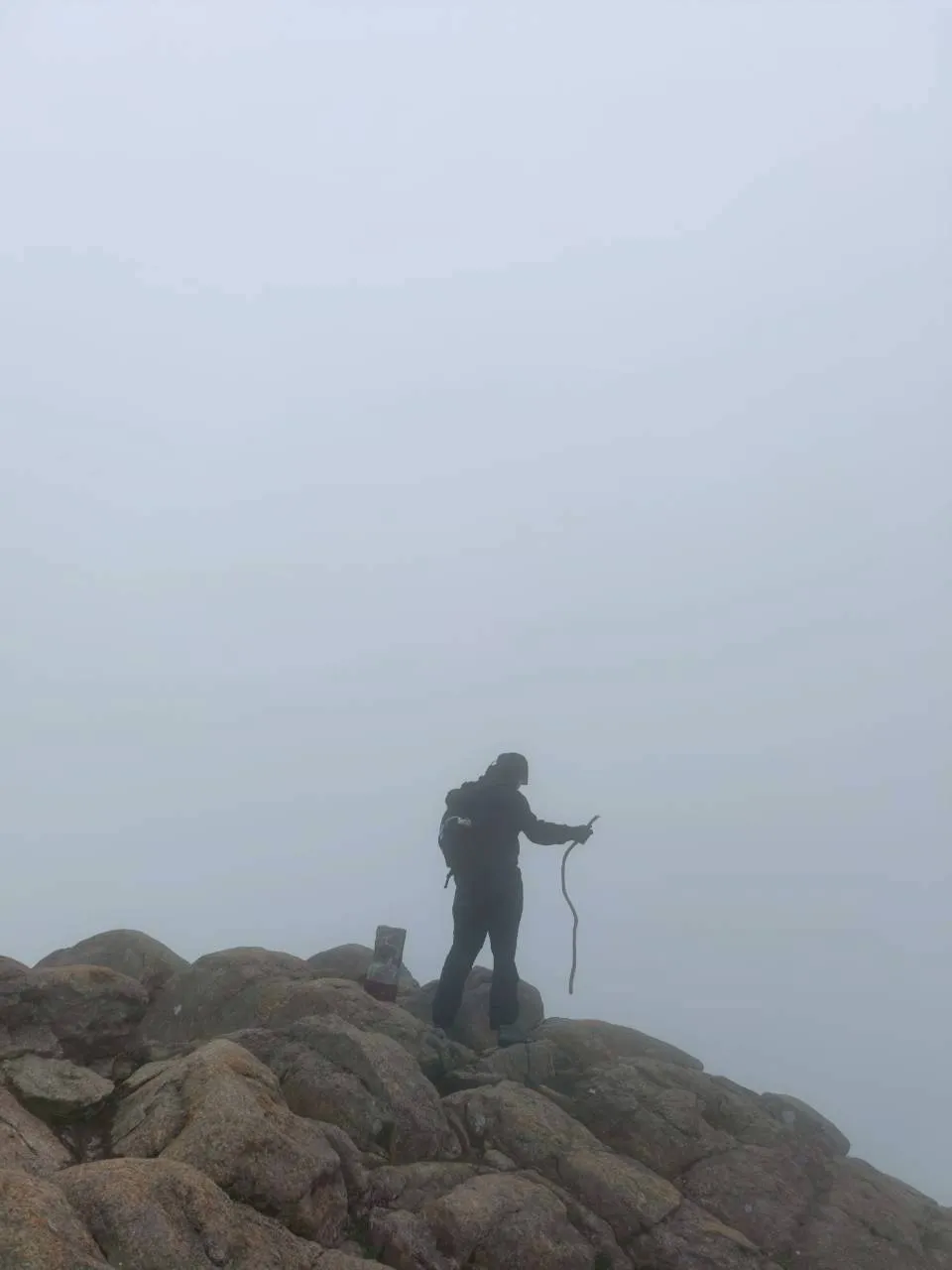 濃霧の中、石鎚山天狗岳の岩の上に立つ登山者のシルエット。